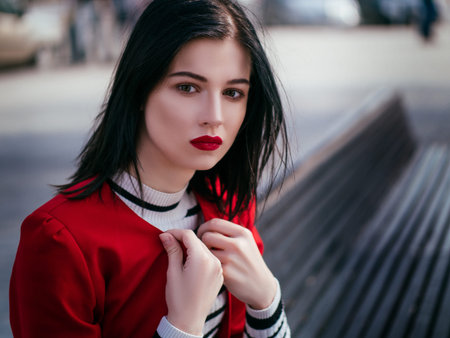 Beautiful glamorous brunete girl in a red jacket posing