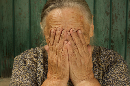 86 years old grandmother   covered his face with hands and criesの写真素材