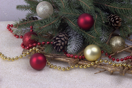 Christmas decoration with bead red silver and golden balls stars snowflakes natural fir branches and cones on shiny fabric as a backgrondの写真素材