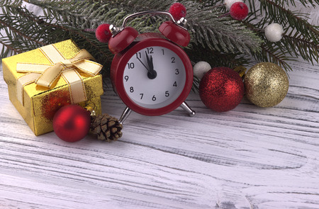 Christmas Xmas New Year holiday decoration with gift box red alarm clock cone natural fir branches golden ball on white wooden background, close upの写真素材