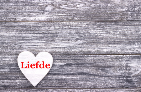 Decorative white wooden heart on grey wooden background with lettering Love in Dutch. Valentines day card. Weddingの写真素材