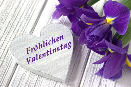 Still life with heart sign iris flowers on white wooden background. Wedding. Valentines Day greeting card with text Happy Valentines Day in German. Loveの写真素材