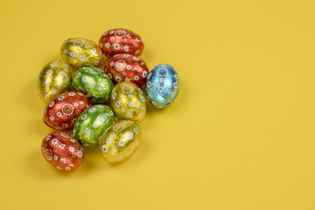 Chocolate easter eggs foil on yellow background