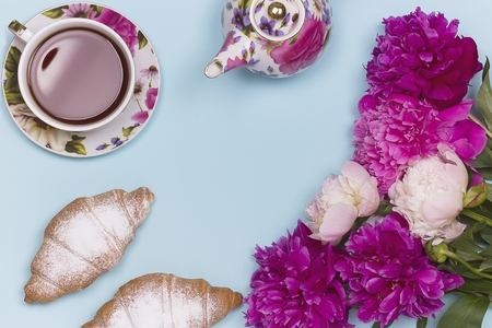 Peony flowers croissant teacup and teapot on blue backgroundの写真素材