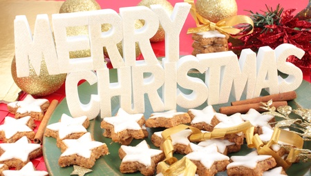 A white Merry Christmas sign above a plate of star-shaped cinnamon cookies.の写真素材