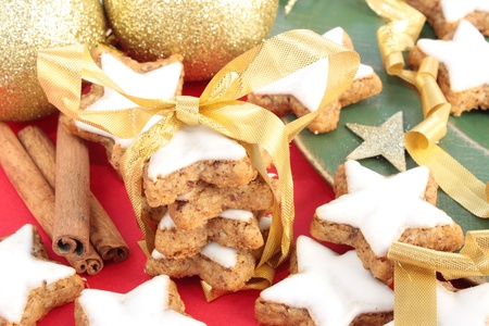Star-shaped cinnamon cookies tied up to give as a gift. Decorated with gold, red and green Christmas decorations.の写真素材