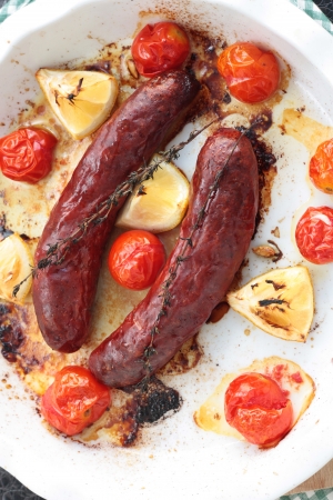 Baked sausages with cherry tomatoes, lemon and thymeの写真素材