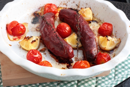 Baked sausages with cherry tomatoes, lemon and thymeの写真素材