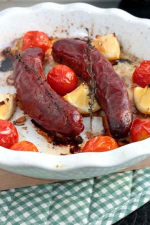 Baked sausages with cherry tomatoes, lemon and thymeの写真素材
