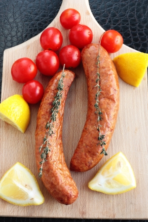 Sausages with cherry tomatoes, lemon and thymeの写真素材