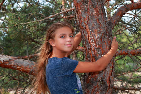 Child girl hugging a tree in the forest. Love of nature.の写真素材