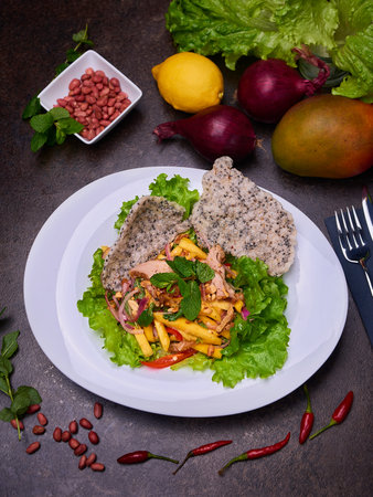 Duck and mango salad. Pan-Asian dish setup on the dark tableの写真素材