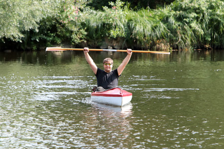 Young man in the red kayak while fishing in the river