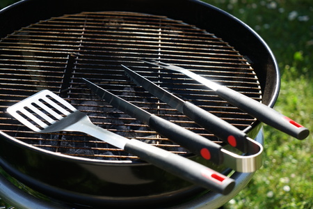 Cutlery for sausages barbecue with a charcoal barbecue in the gardenの写真素材