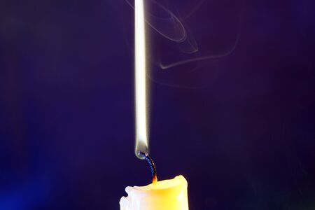 Yellow candle with smoke and flame photographed in the studio with color foils before the flashesの写真素材