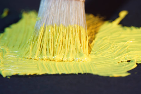 Yellow green oil paint freshly photographed from the tube for artists with brush on black background