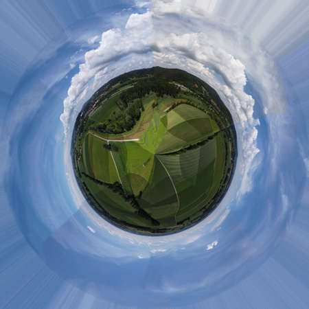 Spherical abstract panoramic aerial view in a field with fantastic beautiful clouds and curvature of space like a small planetの写真素材