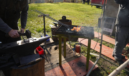 Blacksmith with red hot iron and open charcoal fire at work