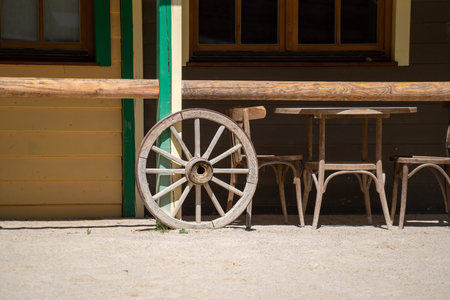 Wooden wheel and chairs in the yard of a country house.