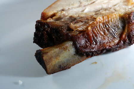 grilled pork ribs on a white plate, closeup of photo