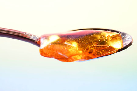 Close up of a spoon full of amber over a white background.の写真素材