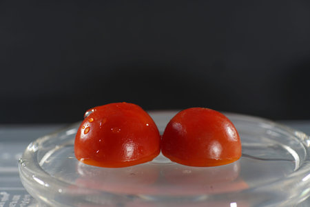 Cherry tomatoes on a glass plate with water drops on a black background