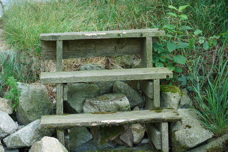 Wooden bench in the park, with grass and stones in the background
