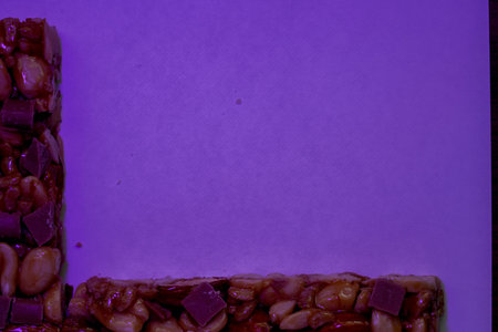 Candy bar with peanuts on a purple background. Place for text.