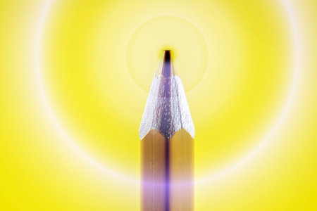pencils on a yellow background with a light bulb in the centerの写真素材