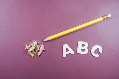 Wooden letters ABC and pencil on a purple background. Back to school.