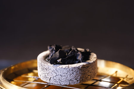Charcoal in a bowl on a black background. Selective focus.