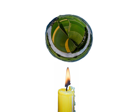 Glass globe with green grass and burning candle on a white background.の写真素材