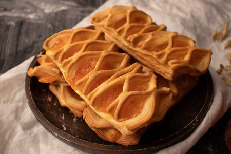 The jam rolls are in a brown wooden plate on a white tablecloth.