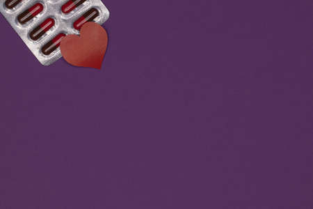 A package of pills with a heart on a purple background, a place under the text. Epilepsy Day. Purple day.の写真素材
