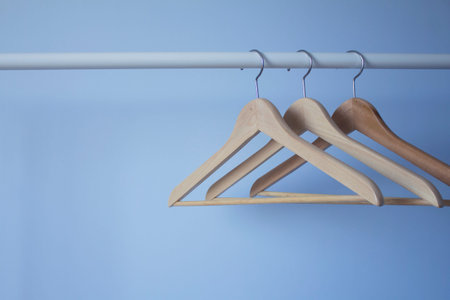 Three wooden hangers for clothes on a metal bar