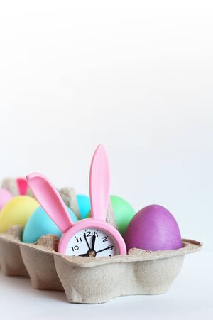 Color Easter eggs and pink watch in the form of a rabbit in paper packingの写真素材