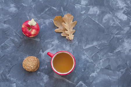 Red cup of tea, cookies and apples on a concrete backgroundの写真素材