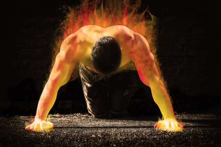 Young fit man in fire showing his muscles -- toned and stylized photoの写真素材