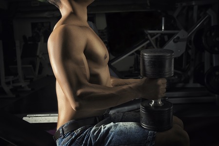 Close up of strong muscular bodybuilder guy doing exercises with weights.の写真素材