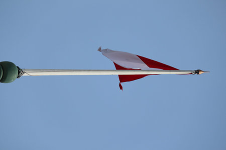 The flag of Austria on a pole with blue sky in the backgroundの写真素材