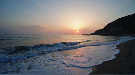 Stunning sunset over calm ocean waters washing onto sandy beach with distant mountain silhouetteの素材