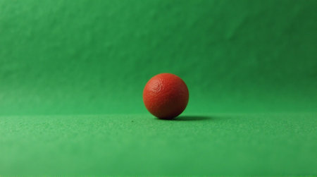 Vibrant orange ball casting shadow on bright green surface perfect for abstract designs and creative conceptsの素材