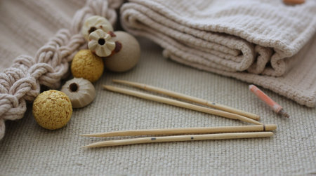 Knitting needles rest with yarn and wooden embellishments, inspiring craft projects and handmade designs with a cozy, textured background.の素材