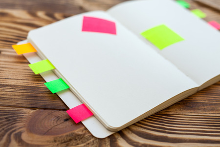 Open notepad with office supplies. Open notepad lies on a wooden desktop with marker, pencil, pen and stickersの写真素材