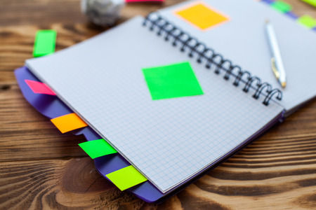 Open notepad with office supplies. Open notepad lies on a wooden desktop with marker, pencil, pen and stickersの写真素材