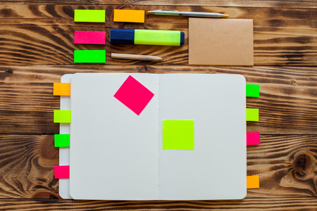 Open notepad with office supplies. Open notepad lies on a wooden desktop with marker, pencil, pen and stickersの写真素材