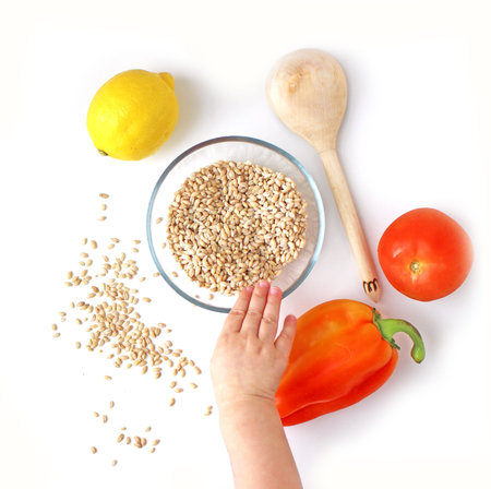 Pearl Barley in a bowl with baby hand, flat lay view on white bacground, healthy eating concept, photo for lifestyle blogsの写真素材
