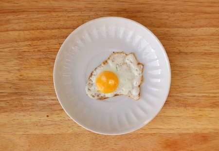 Fried Quail egg on a white saucer flat lay on wooden boardの写真素材