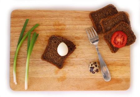 Boiled Quail egg on wholegrain bread and slice of tomato flat lay on wooden board