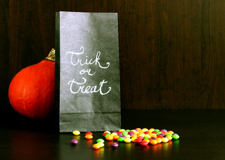 Black paper bag with candy with hand drawn sign Trick or Treat, pumpkin, concept for Halloweenの写真素材